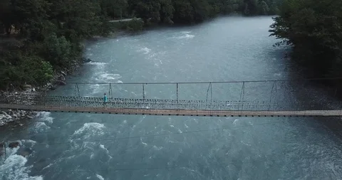 Suspension bridge surrounded by lush green forest - Top down aerial view 스톡 동영상 100588660