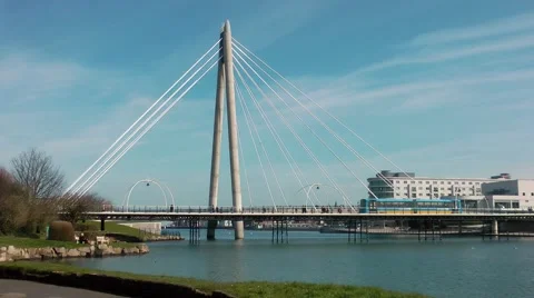 Suspension bridge train crossing blue sky clouds water Stock Footage 48680379