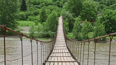 Suspension flyer rustic wooden bridge over mountain river, idyllic green nature Stock-Footage 243764151
