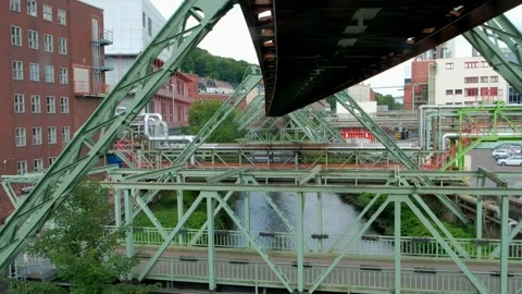 Suspension monorail system tracking above a river next to modern buildings Vídeos de archivo 337292786