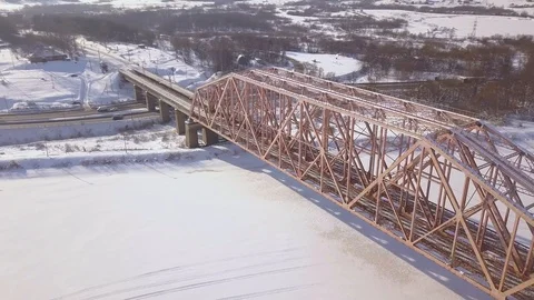 Suspension train bridge through winter river and car traffic on snowy highway Stock Footage 88569800