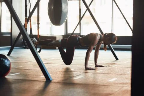 Suspension Training. Side view of young caucasian fitness woman in sportswear Stock Photos