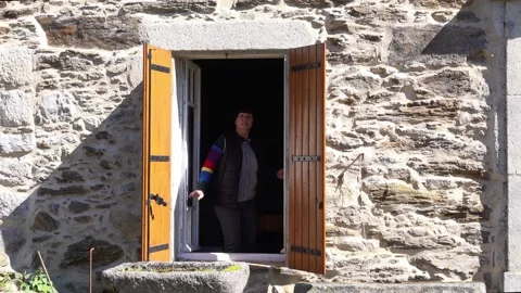 Suspicious eldery woman close window and courtains in an old stone country ho Vídeos de archivo 154369161