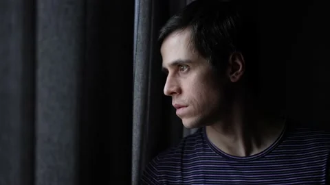 Suspicious man looking out of the window Video stock 148336341