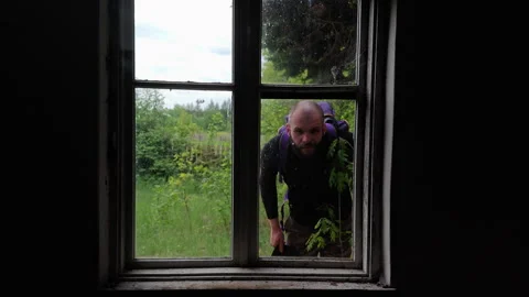 Suspicious man with sinister expression peering through old window Stock Footage 336970733
