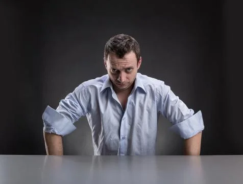 Suspicious man sits at table Stock Photos