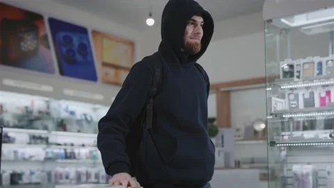 Suspicious man steals in a gadget store. The thief hides the goods and runs away Stock Footage 229171469