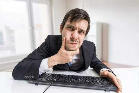 Suspicious man is working with computer and looking on screen. Stock Photos
