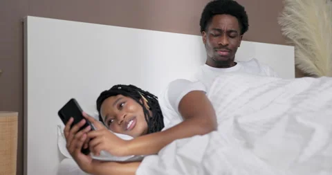 Suspicious young american dark skinned black husband laying in bed with her wife Stock Footage 262576624