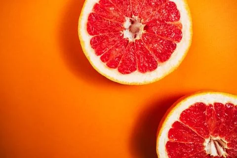 Сut grapefruit on the orange background. Stock Photos