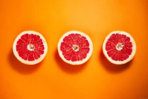 Сut grapefruit on the orange background. Stock Photos