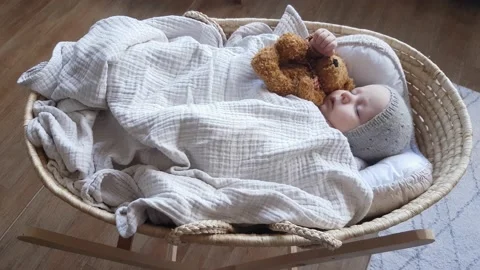 Сute baby boy sleeping in a wicker basket in an embrace with a teddy bear Stock Footage 165462732