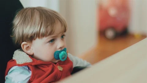 Сute little kid with soother while watching while watching TV. 库存影片 128748995
