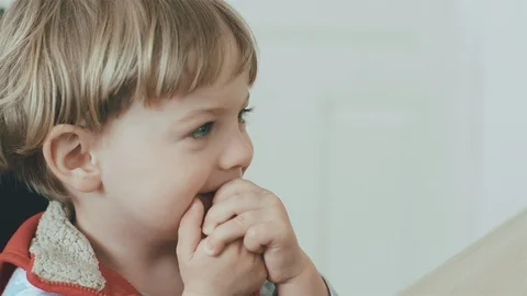 Сute little kid while watching TV. Young boy with blue eyes 库存影片 128747346