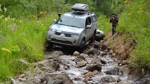 An SUV and a jeep hardly overcomes a natural obstacle Stock Footage 129737745