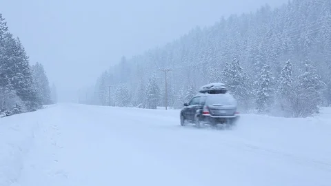 SUV car with rooftop cargo box driving on snow covered road in winter Stock Footage 107054088