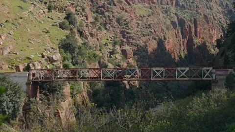 SUV Crossing A Red Truss Bridge Over A Rocky Gorge In Morocco Stock Footage 340595347