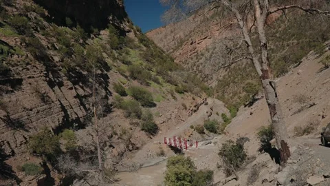 SUV Crossing Small Red Bridge Over River in Steep Rocky Gorge in Atlas Stock Footage 340221115
