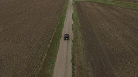 SUV driving down a dirt road surrounded by fields Stock Footage 81722664