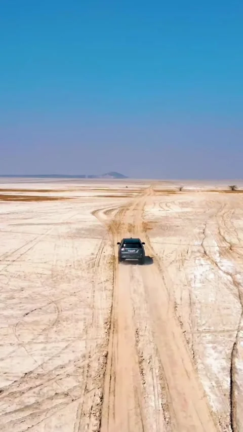 SUV driving off-road on a remote dirt track through a vast arid desert landscape Video stock 338046362