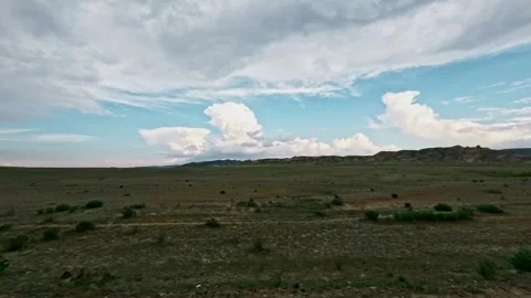 SUV driving off-road through expansive landscape with clouds in the distance Stock Footage 340956548