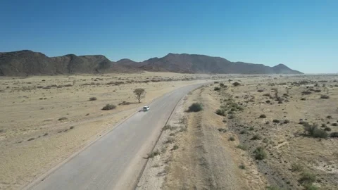 SUV Driving Through Desert Toward Mountains - Aerial Follow, Sesriem, Namibia Stock Footage 346540410