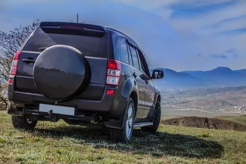 SUV on the field under a cloudy sky. Stock Photos