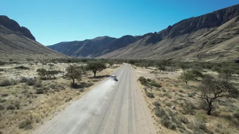 SUV Kicking Up Dust in Mountain Valley - Aerial Follow, Naukluft, Namibia Stock Footage 346540375