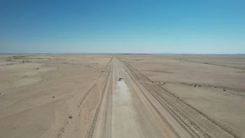 SUV Leaving Dust Trail on Straight Namib Desert Track - Aerial Follow Shot Stock Footage 346540360