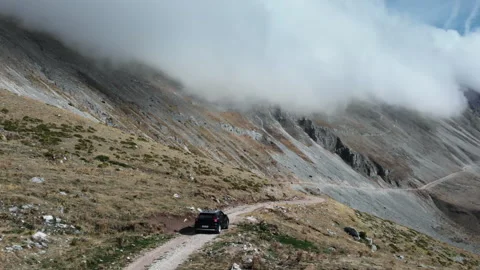 SUV Navigating a Remote Mountain Path Under Low-Hanging Clouds 動画素材 333027177