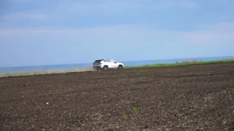 SUV navigating through open field, kicking up dust while moving towards the Stockbeeldmateriaal 347874733