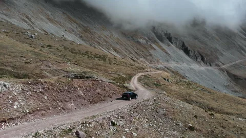 SUV Navigating a Winding Mountain Path Under Dense Cloud Cover 库存影片 333028755