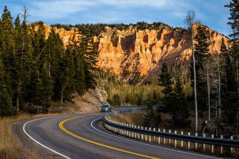 SUV or Minivan driving down winding canyon road in the Utah desert with sunse Stock Photos