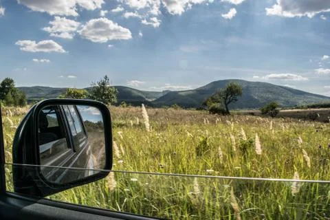 Suv rear view mirror shot while off roading on a beautiful field. Stock Photos