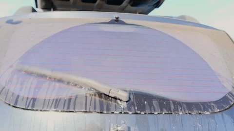 SUV rear window wiper operating with washer fluid spraying and clearing dirty Stock Footage 333617327