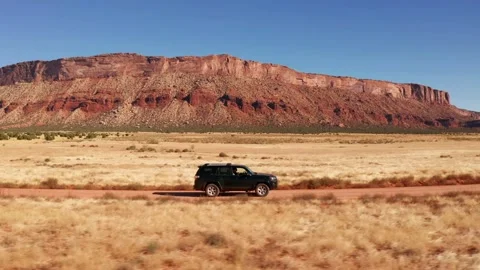 SUV Off-Roading by Red Rock Cliffs - 4K Video Stock Footage 339506694
