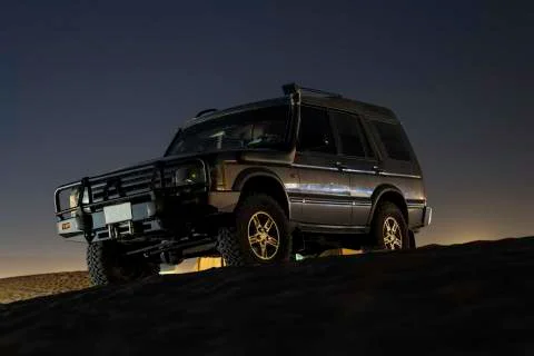 An SUV standing on a dune at sunset Stock Photos