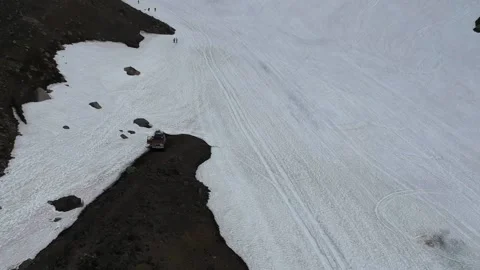 The SUV stands in the middle of a snowy plain in the mountains. Travelling Stock Footage 141296430