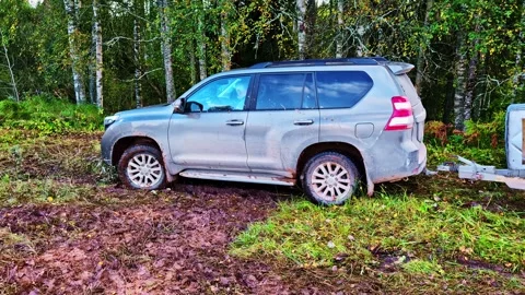 SUV Vehicle Stuck Deep In Muddy Patch Beside Forest With Tires Partially Buried Video stock 318869077