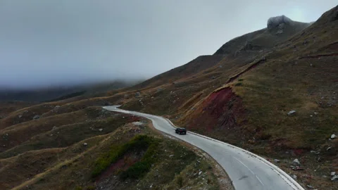 SUV Winding Through Misty Mountainous Terrain on a Serpentine Road Vidéo 333028197