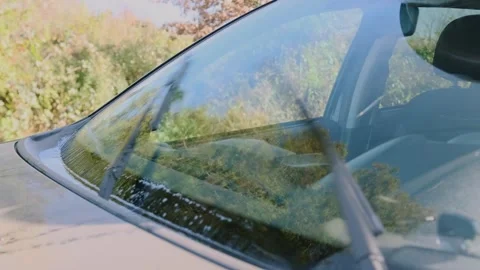 SUV windshield wipers operating with washer fluid spraying across front glass Stock Footage 333617322