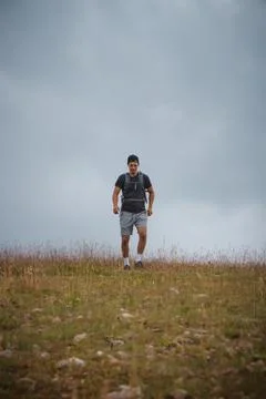 Swarthier type of man is running down a gravel hill, checking his every step  Stock Photos