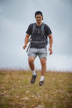 Swarthier type of man is running down a gravel hill, checking his every step  Stock Photos