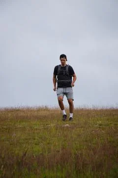 Swarthier type of man is running down a gravel hill, checking his every step  Stock Photos