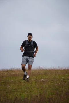 Swarthier type of man is running down a gravel hill, checking his every step  Foto stock