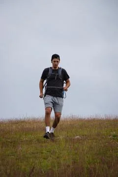 Swarthier type of man is running down a gravel hill, checking his every step  Stock Photos