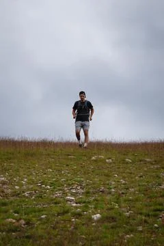 Swarthier type of man is running down a gravel hill, checking his every step  Foto stock