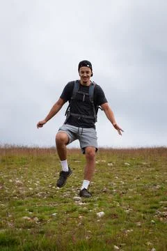 Swarthier type of man is running down a gravel hill, checking his every step  Foto stock
