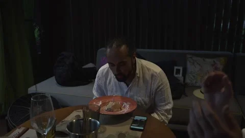 A swarthy man with a beard in a hat blows out a candle on a festive dessert Stock Footage 221857129