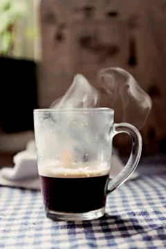 Sweating cup of coffee with steam on the table Stock Photos
